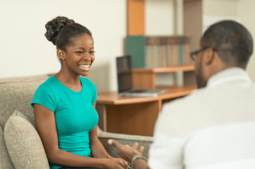 Smiling black female receives counseling from black professional