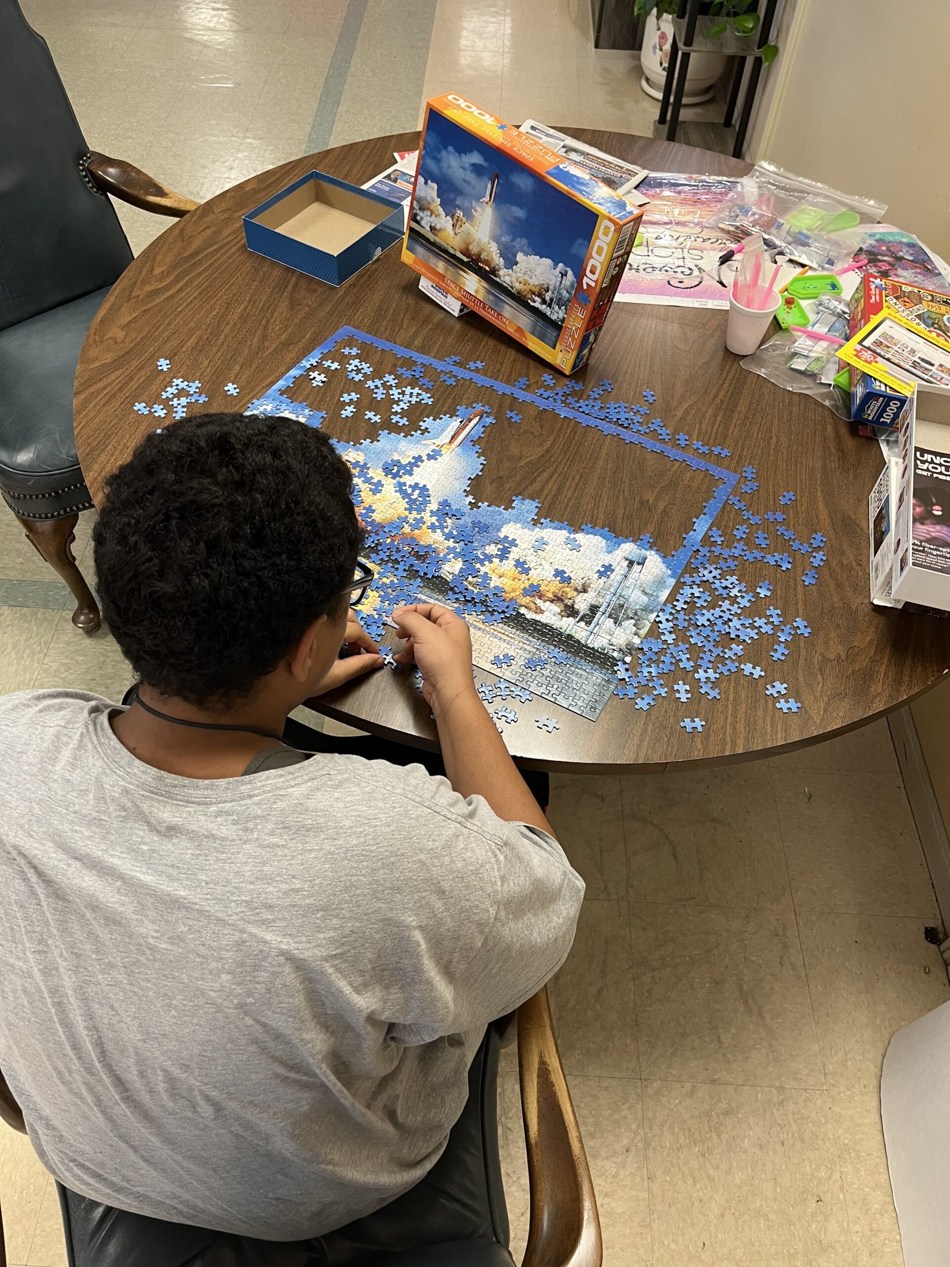 Person completing a puzzle at a round table.